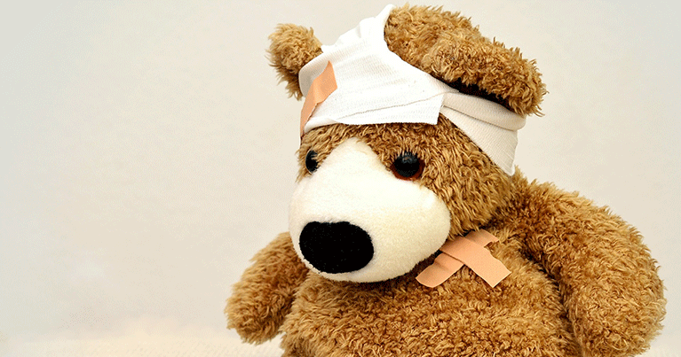 En teddybjörn med bandage kring huvudet och plåster på bröstet