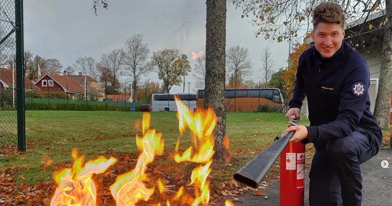 En man som står på knä och släcker en eld med handbrandsläckare.