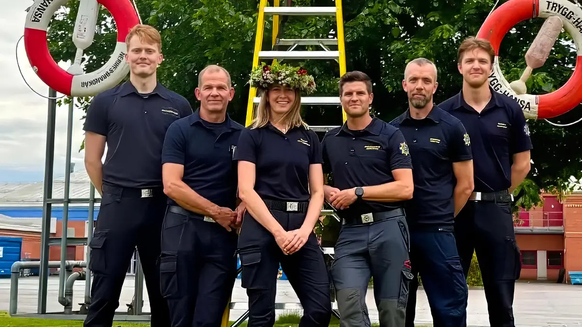 Fem personer står uppradade framför en midsommarstång