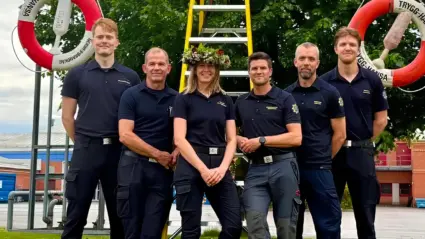 Fem personer står uppradade framför en midsommarstång
